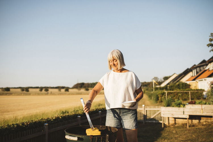 Woman in garden having barbecue