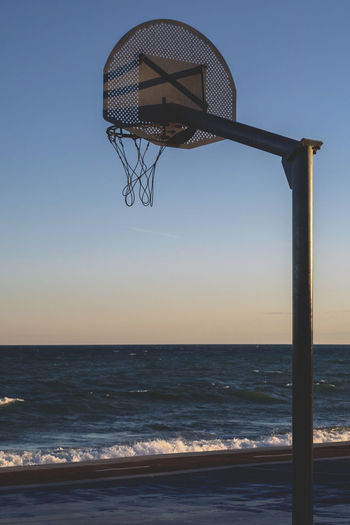 Basketball hoop on sea against clear sky