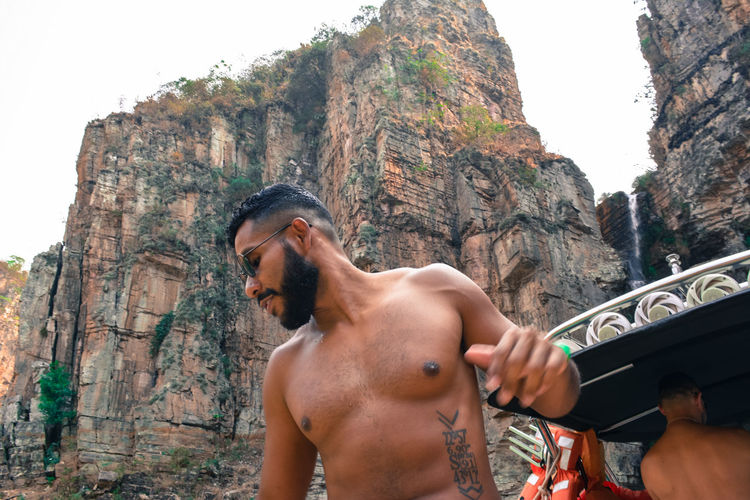 Rear view of shirtless man standing against mountain