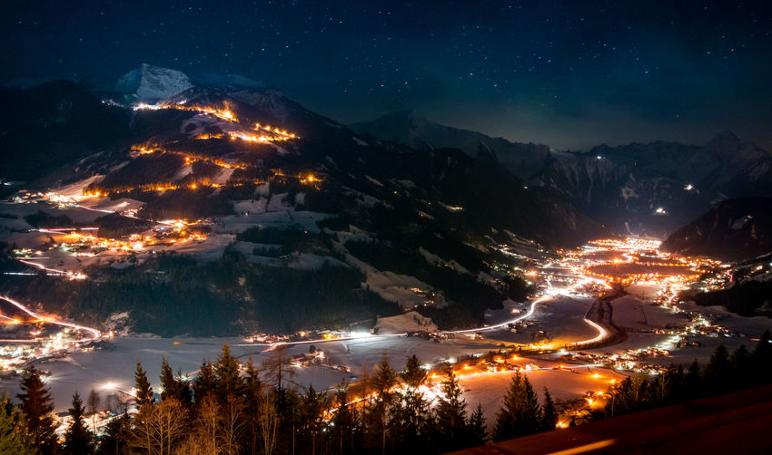 Scenic view of illuminated villages and mountains at night