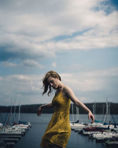 Full length of woman standing at harbor against sky
