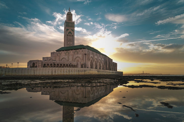 Reflection of mosque by sea during sunset