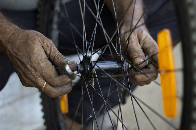 The old man working on motorcycle tire with tools close view in a service shop using finger in hands