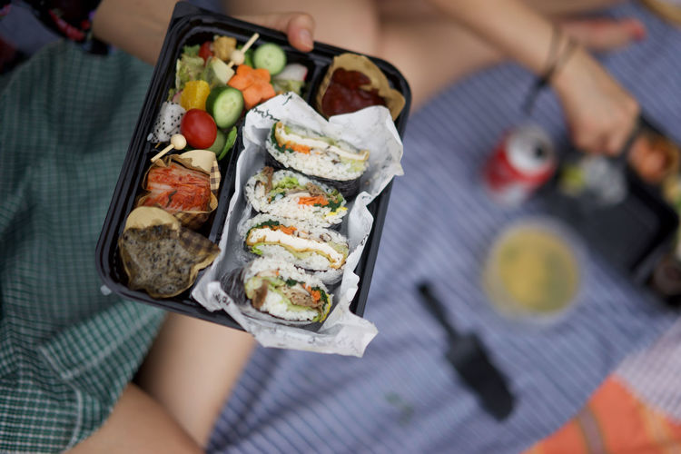 Cropped image of person holding sushi in container
