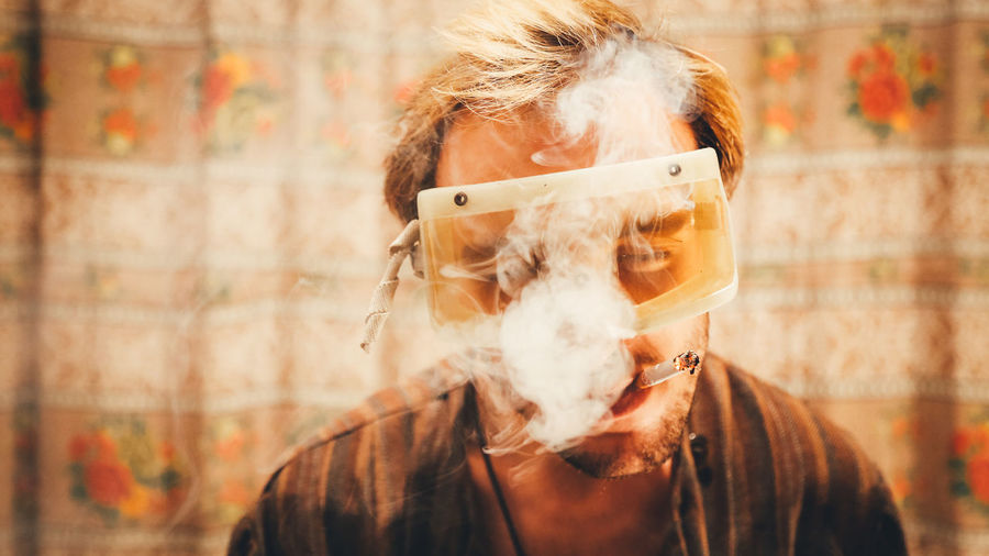 Man wearing protective eyeglasses while smoking cigarette