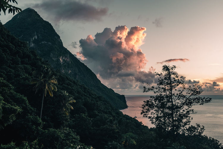 Scenic view of sea by mountains against sky during sunset