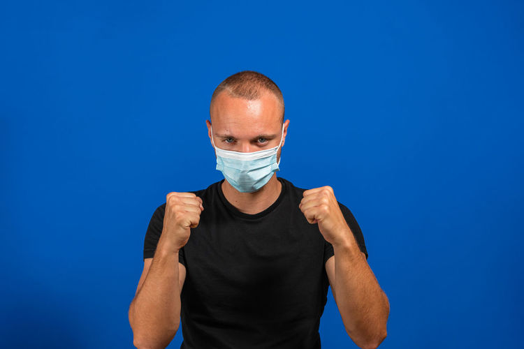 Portrait of man standing against blue background