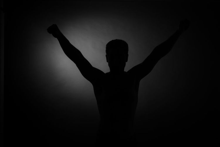 Rear view of silhouette person against black background