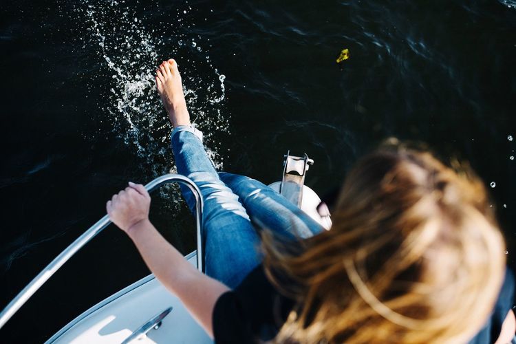 High angle view of woman splashing water while sitting on boat