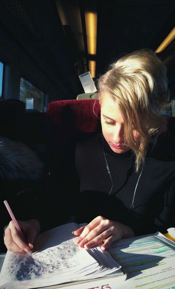 Young woman writing on book while traveling in train