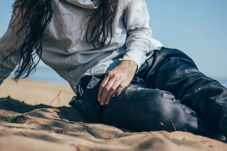 Midsection of woman sitting on sand