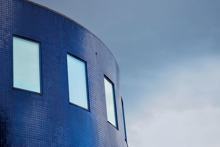 Low angle view of modern building against blue sky