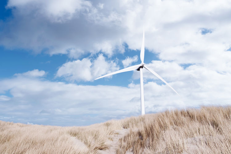 Wind turbine behind grass covered dunes