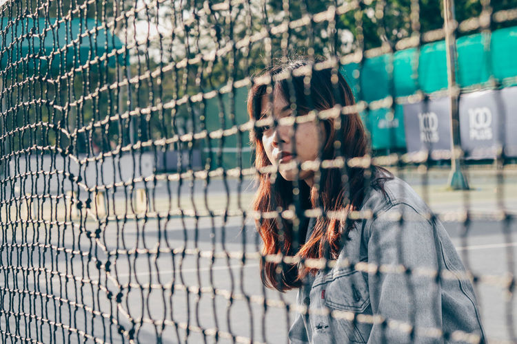 Young woman seen through chainlink fence