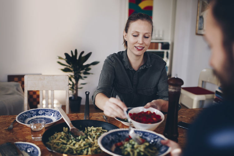 Happy young woman having food at home