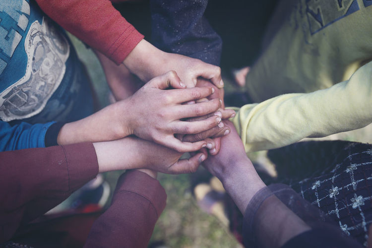Midsection of children stacking hands while huddling outdoors