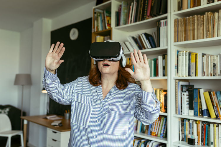 Woman using virtual reality glasses while standing at home