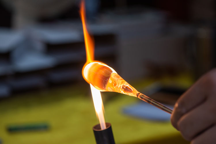 Close-up of hand holding molten glass in workshop