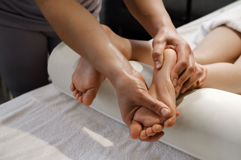 Child foot massage treatment by professional massage therapist in spa resort. healthcare concept. 