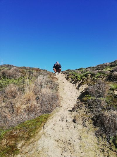 Low angel view of man crouching against sky