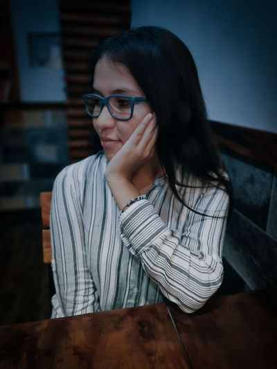 Young woman looking away while sitting at table in cafe