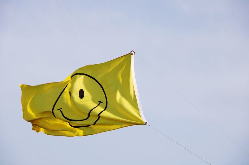 Low angle view of yellow flag against sky