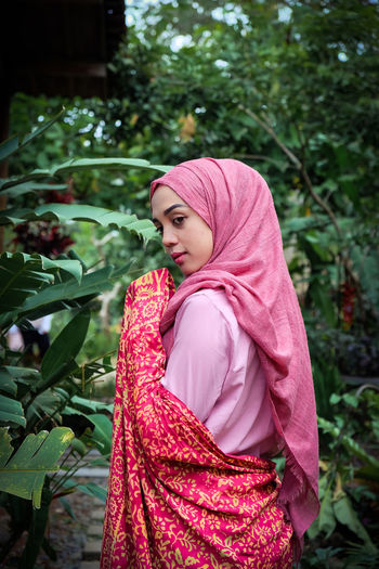 Side view of woman wearing hijab standing against plants
