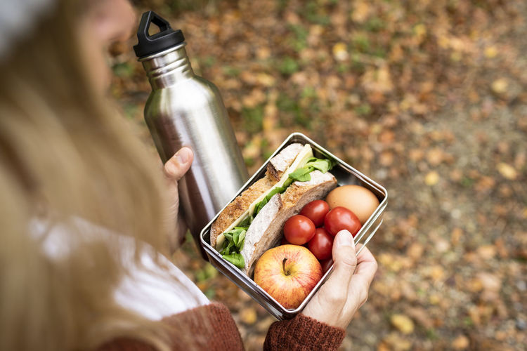 Woman's hand holding food box and water bottle