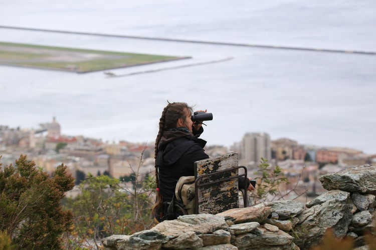 Woman looking through binoculars against sea