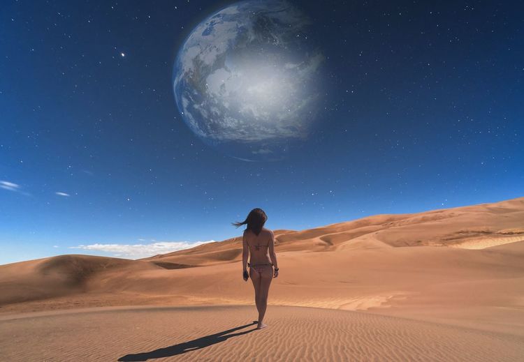 Rear view of woman on desert against sky