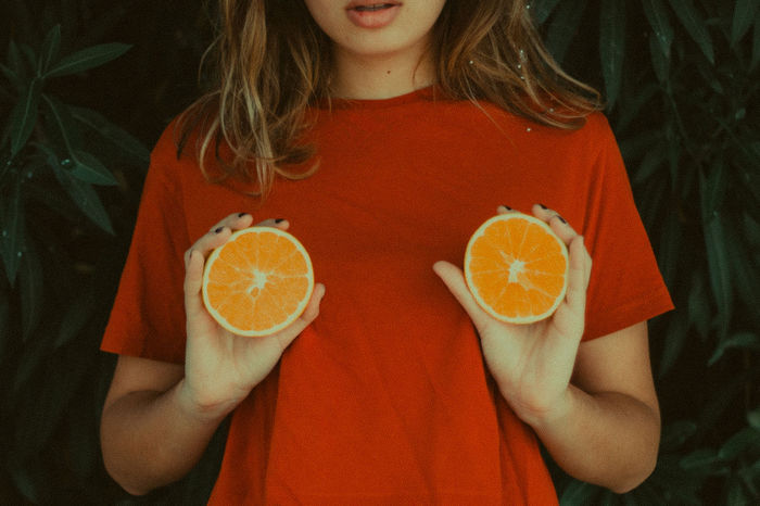 Midsection of woman holding orange slices by plants
