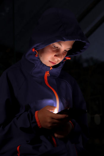  night shot - boy with hoodie on looking at mobile phone with illuminated face