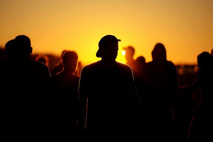 Silhouette people standing on field against clear orange sky