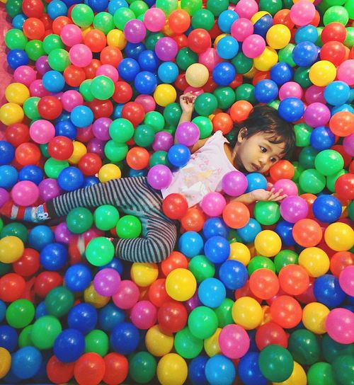 High angle view of girl lying on colorful ball pool