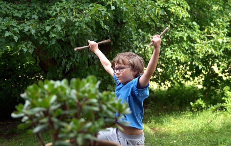 Boy holding sticks while dancing in park