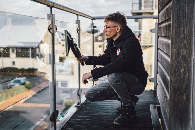 Young man cleaning glass balcony