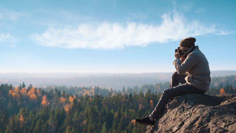 Man sitting on mountain against sky