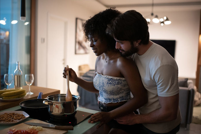 Man helping black girlfriend to cook dinner