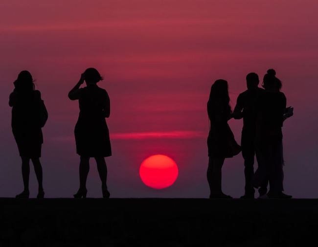 Silhouette people standing against sky during sunset