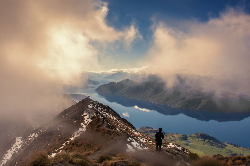 Man standing mountain ridge against sky