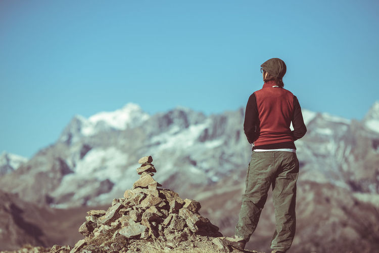Rear view of man standing on cliff against sky