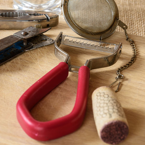 High angle view of peeler and tea strainer on wooden table