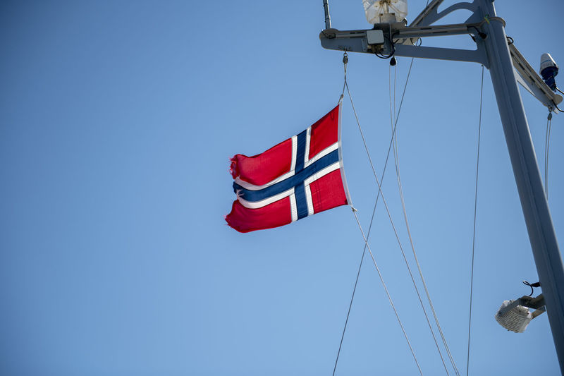 Low angle view of flag against clear blue sky