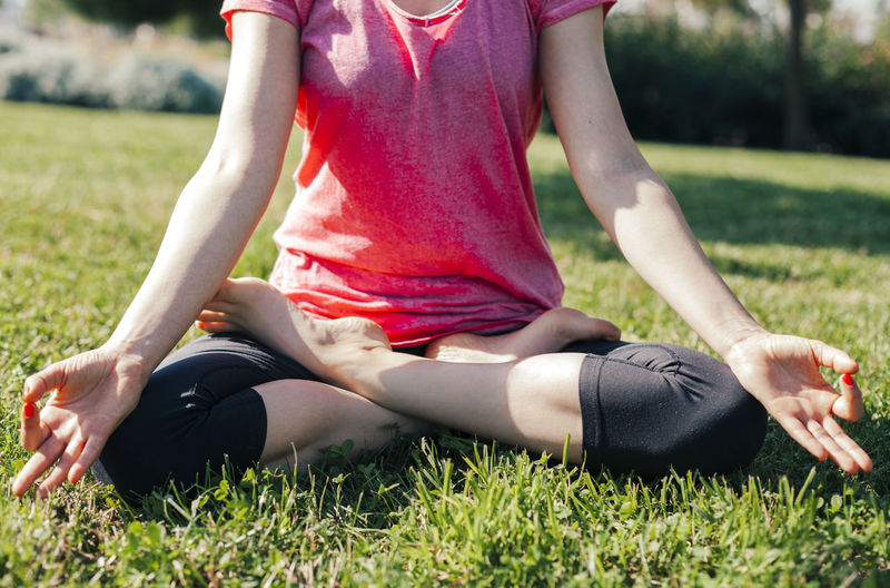 Midsection of woman sitting on field
