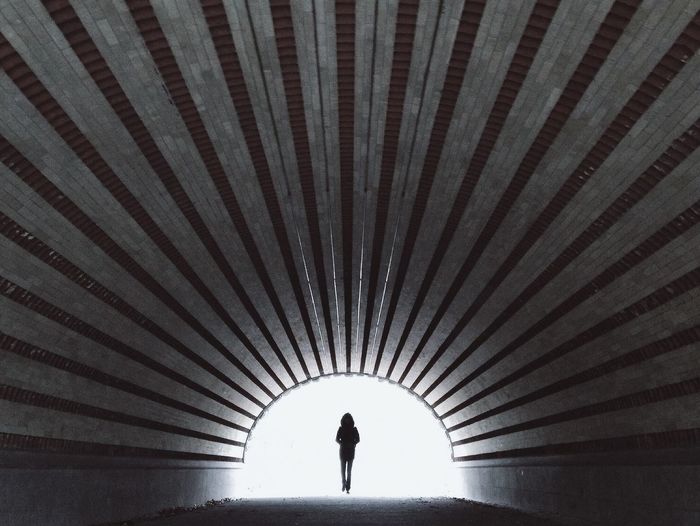 Silhouette person walking in tunnel
