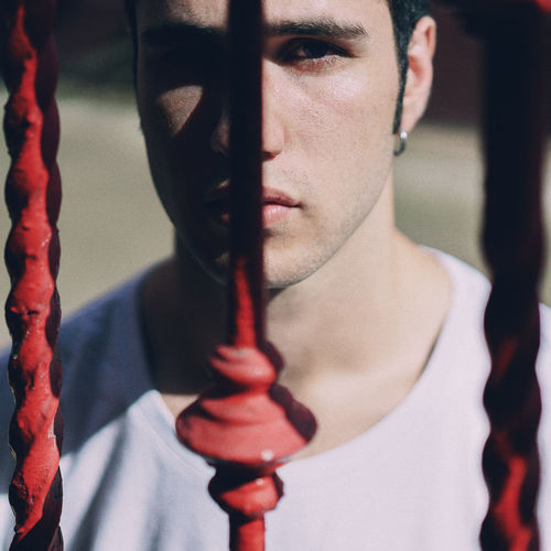 Close-up portrait of young man against fence