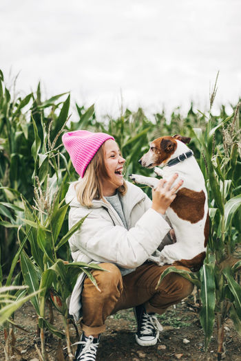 Happy teenage girl hugging her dog jack russell terrier in a field against a background 