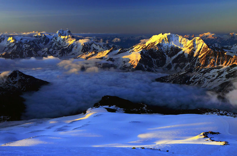 Scenic view of snowcapped mountains covered with cloudscape at sunset