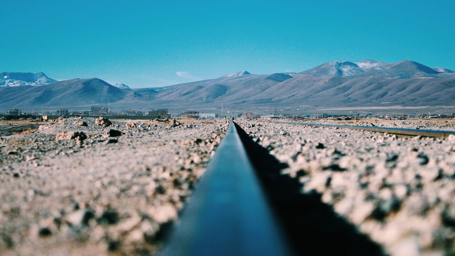 Surface level of railroad tracks against clear blue sky