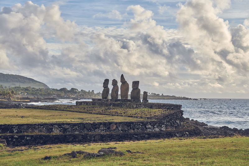 Scenic view of moai statues against cloudy sky
